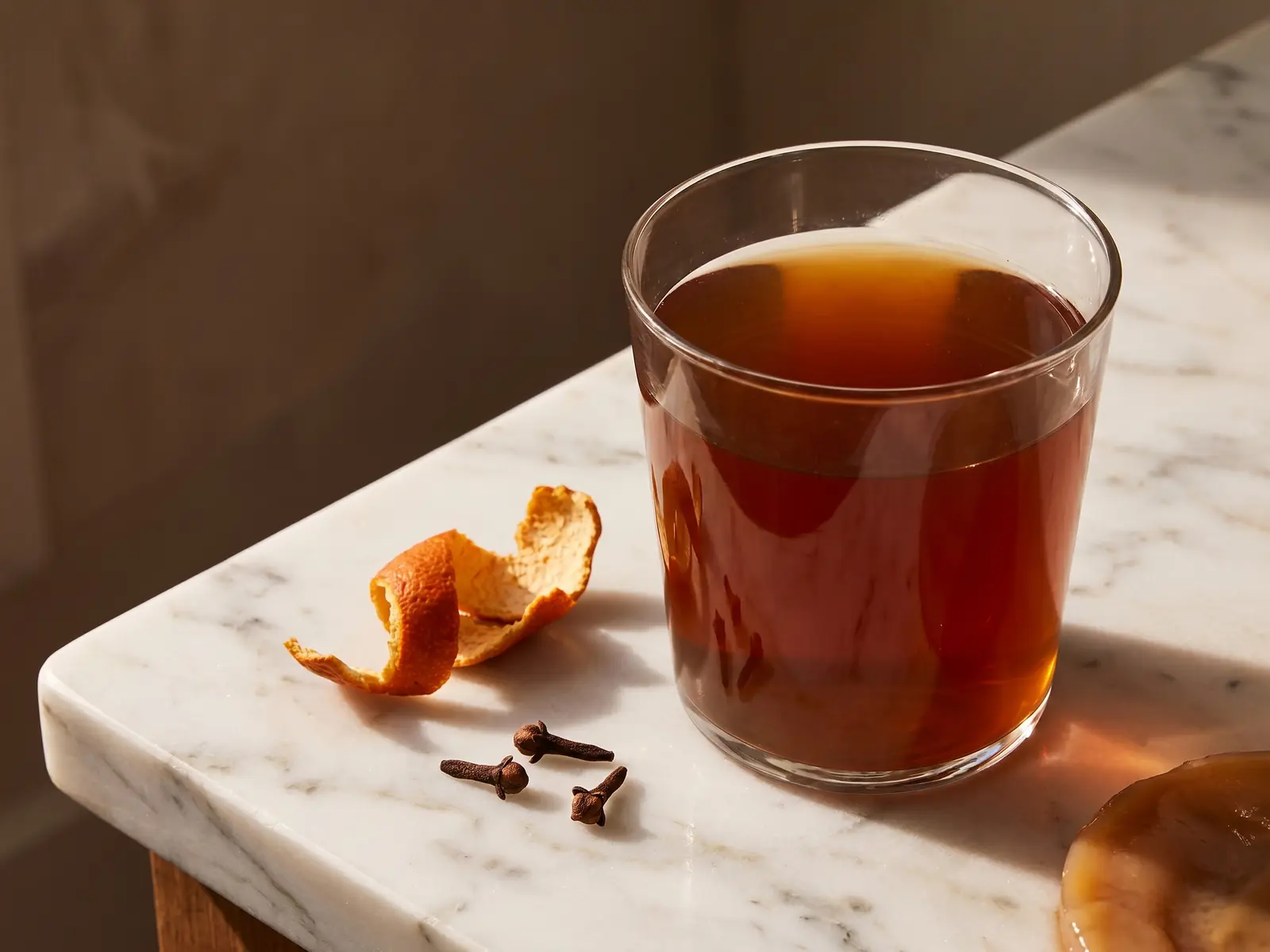 kombucha calorie Kombucha ambrata servita con chiodi di garofano e scorza d’arancia secca su marmo chiaro.